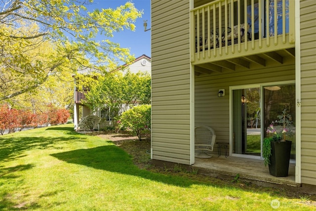 view of grassy yard featuring a balcony