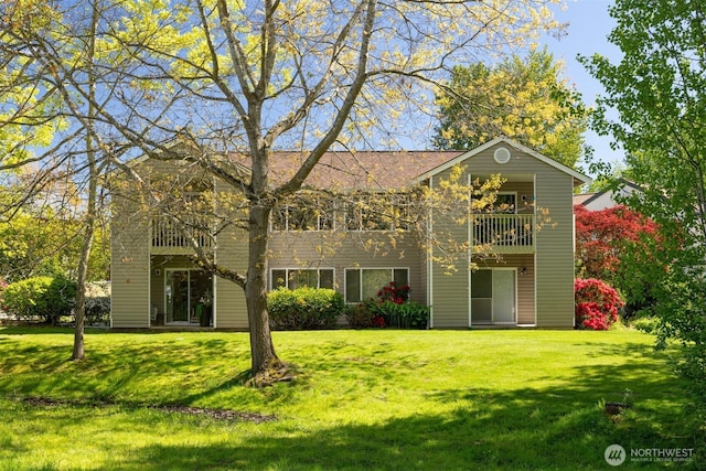 back of house with a yard and a balcony