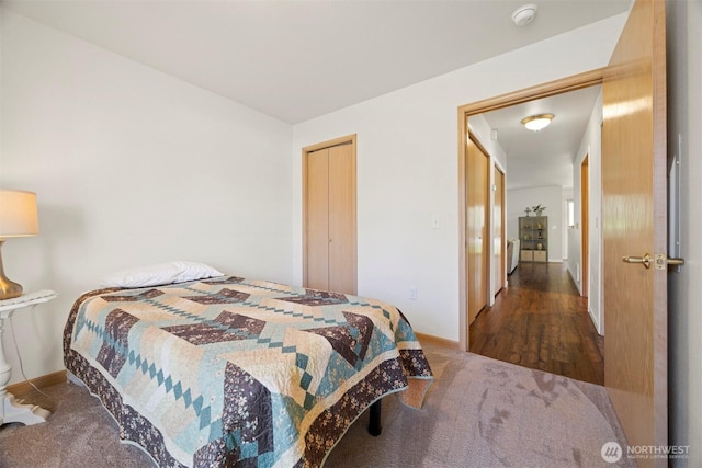 carpeted bedroom featuring baseboards and a closet