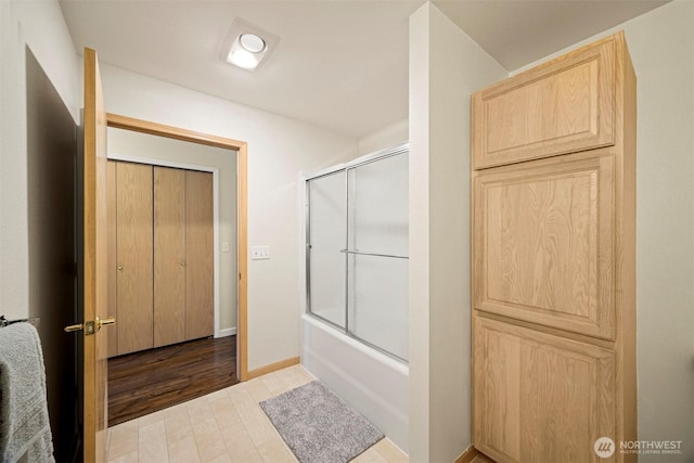 full bathroom featuring combined bath / shower with glass door and baseboards