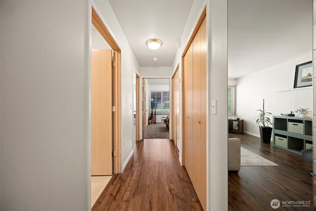 corridor with dark wood-style floors and baseboards