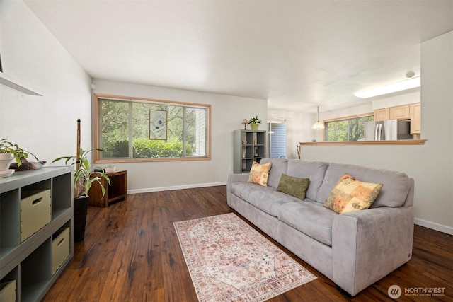 living area featuring dark wood-style flooring, baseboards, and a chandelier