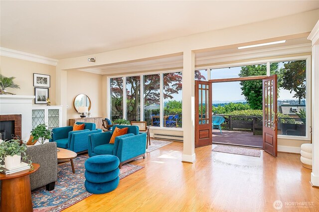 living room featuring wood finished floors, a baseboard heating unit, a fireplace, and crown molding