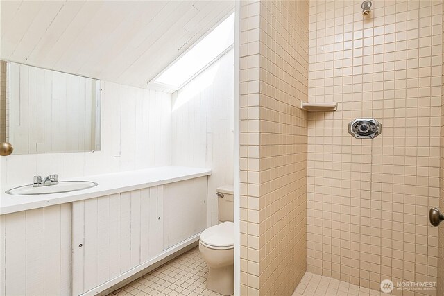 bathroom with toilet, a tile shower, tile patterned flooring, and vanity