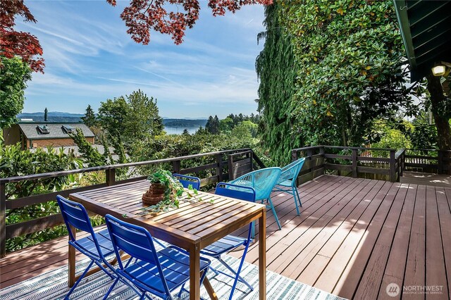 wooden terrace featuring outdoor dining space and a water view