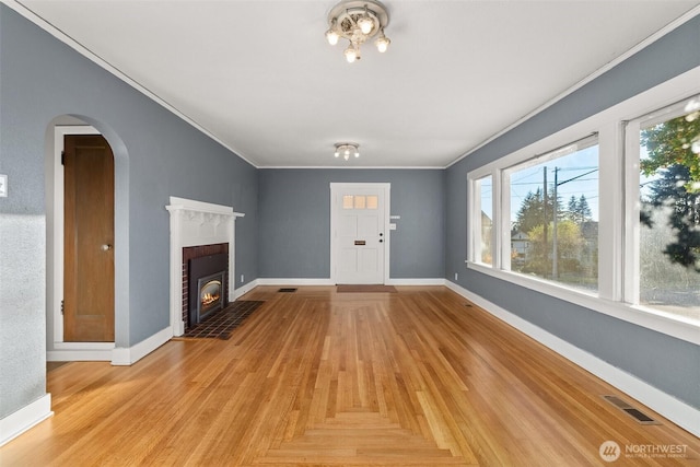 1250 N Broadway St, Aberdeen, WA 98520 - unfurnished living room featuring crown molding, a brick fireplace, arched walkways, and light wood-style floors