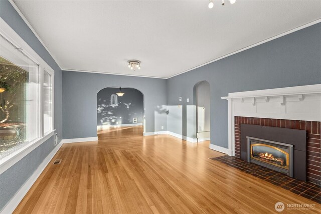 1250 N Broadway St, Aberdeen, WA 98520 - unfurnished living room featuring arched walkways, wood finished floors, a brick fireplace, and ornamental molding