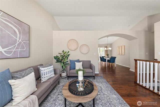 living area featuring arched walkways, vaulted ceiling, wood finished floors, a chandelier, and baseboards