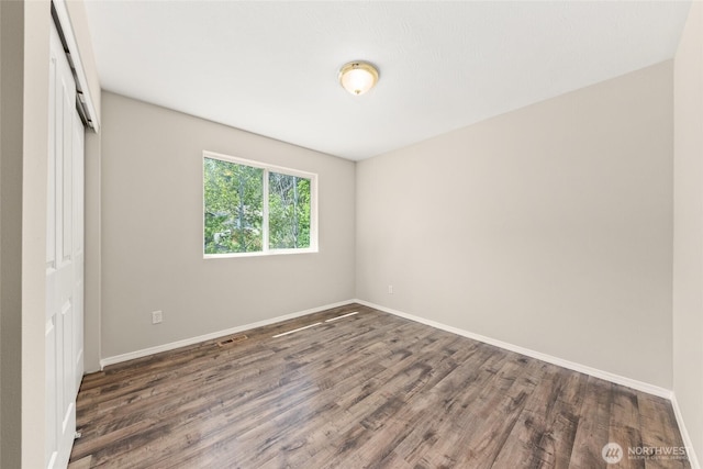 unfurnished room with dark wood-style floors and baseboards