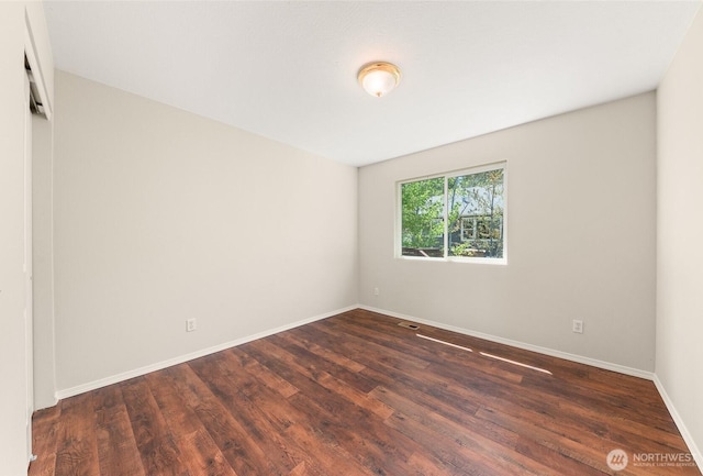empty room featuring baseboards and dark wood-style floors