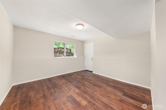 unfurnished room featuring dark wood-type flooring and baseboards