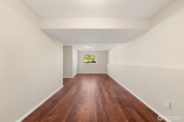 spare room with dark wood-type flooring and baseboards