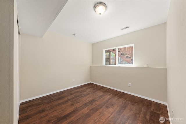 unfurnished room featuring baseboards and dark wood-type flooring