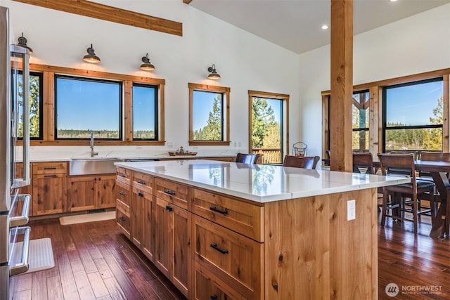 kitchen featuring a sink, dark wood finished floors, a kitchen island, recessed lighting, and a towering ceiling