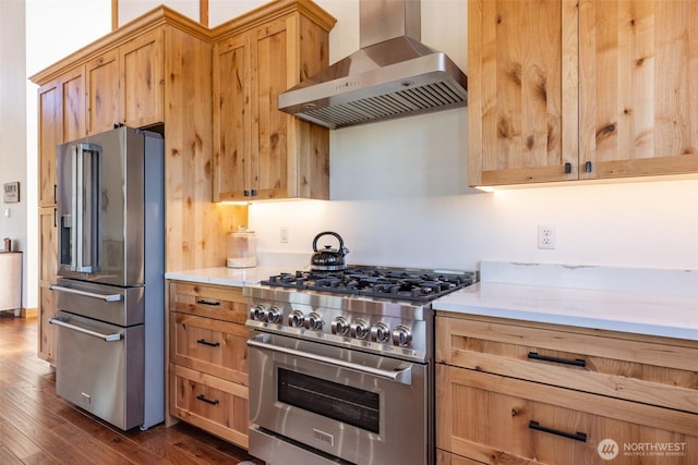 kitchen featuring stainless steel appliances, wall chimney exhaust hood, dark wood-style flooring, and light countertops