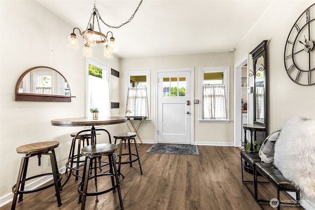 dining room featuring dark wood-type flooring, baseboards, and a chandelier