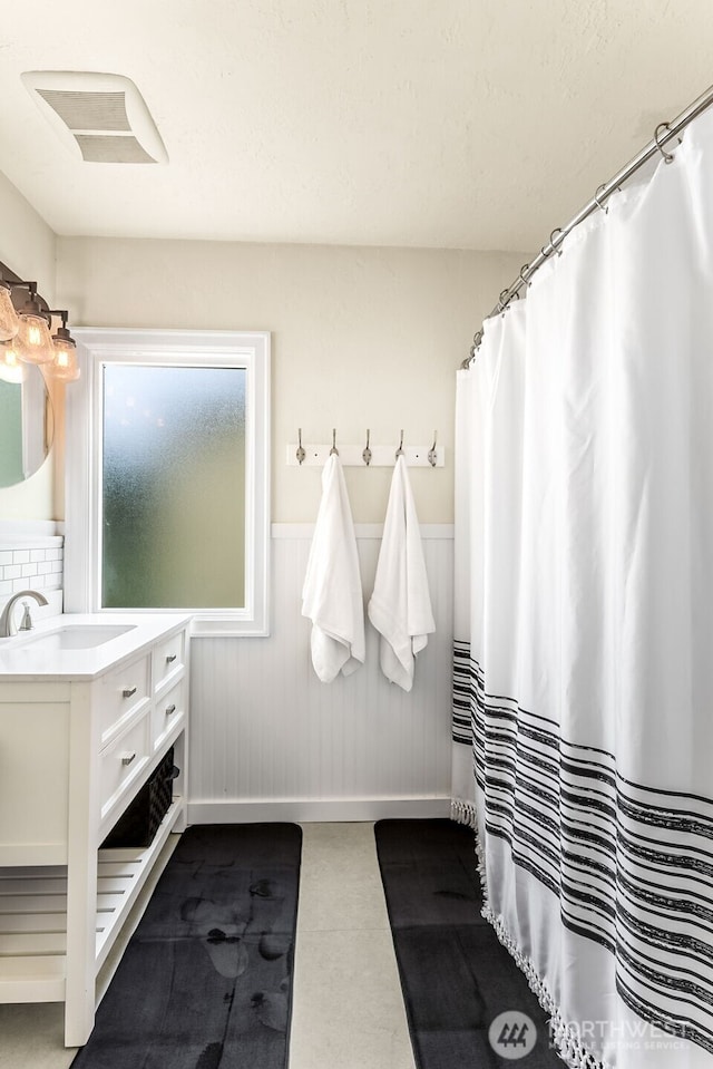 full bathroom featuring wainscoting, vanity, and baseboards