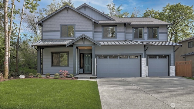 view of front facade with a standing seam roof, an attached garage, concrete driveway, a front lawn, and metal roof