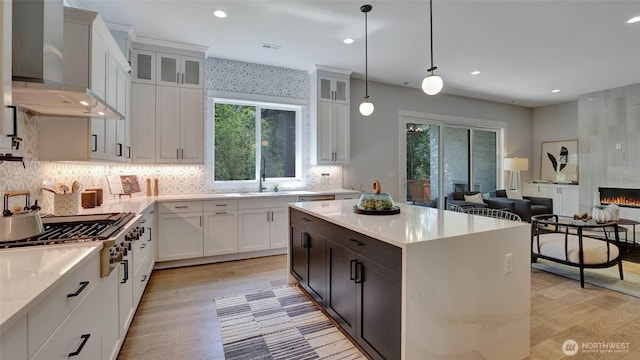 kitchen featuring stainless steel gas stovetop, wall chimney range hood, plenty of natural light, light wood-style flooring, and recessed lighting