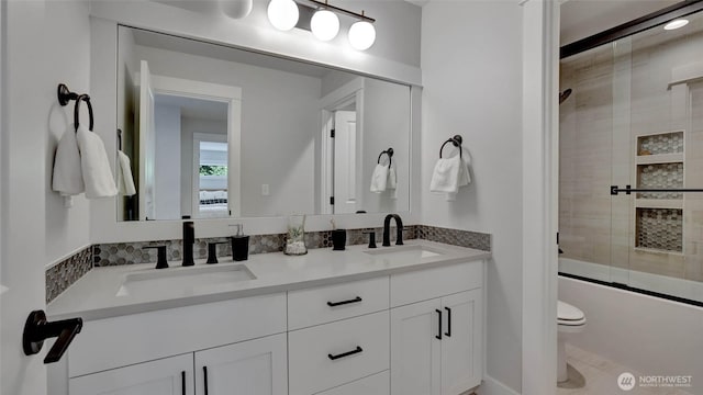 bathroom featuring toilet, double vanity, and enclosed tub / shower combo