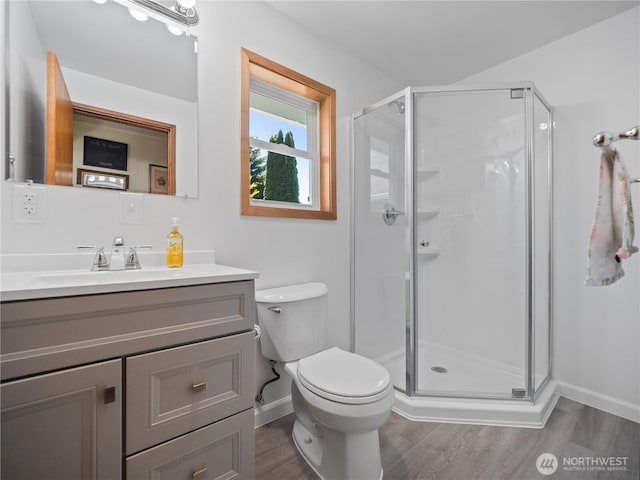 bathroom featuring a stall shower, wood finished floors, vanity, baseboards, and toilet