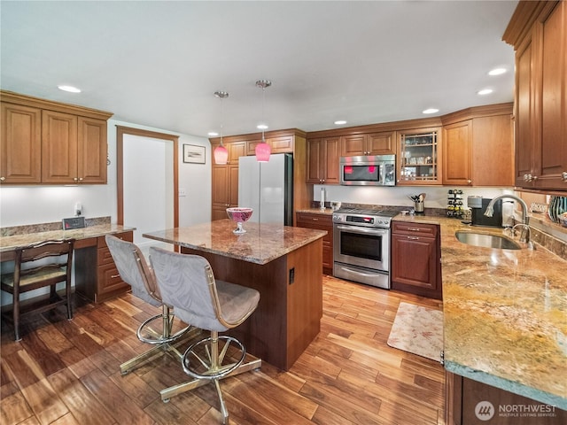 kitchen with stainless steel appliances, a sink, recessed lighting, a kitchen island, and a kitchen breakfast bar