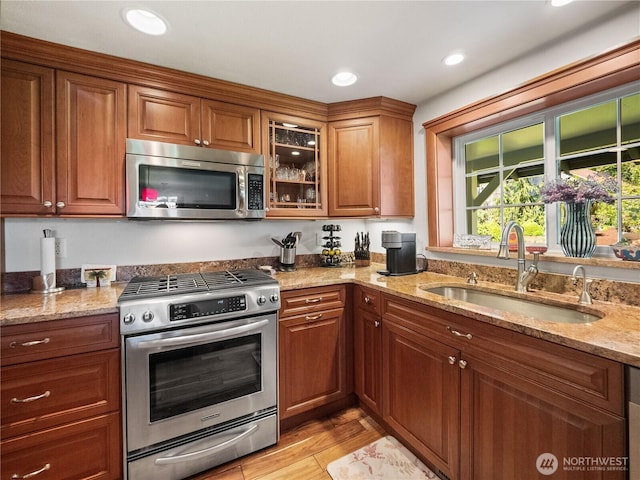 kitchen featuring appliances with stainless steel finishes, a sink, brown cabinets, and recessed lighting