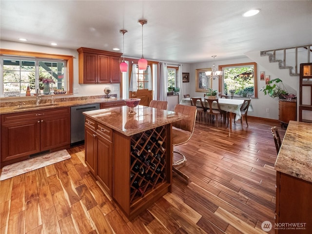 kitchen with stainless steel dishwasher, a sink, recessed lighting, light stone countertops, and wood finished floors