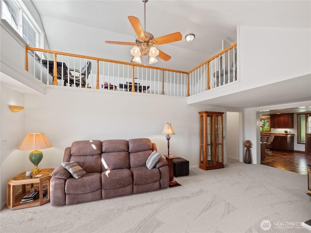 carpeted living room with a towering ceiling, ceiling fan, and baseboards