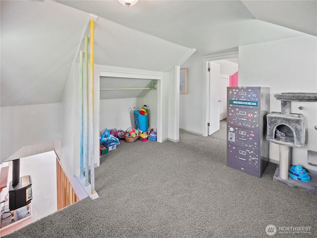 recreation room featuring lofted ceiling, a wood stove, and carpet floors
