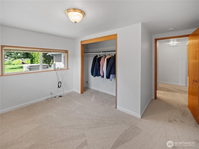 unfurnished bedroom with carpet floors, a closet, and baseboards