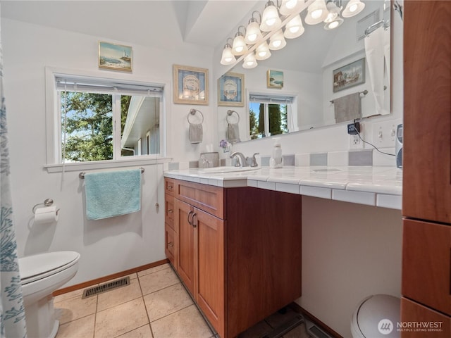 bathroom featuring toilet, healthy amount of natural light, vanity, and tile patterned flooring