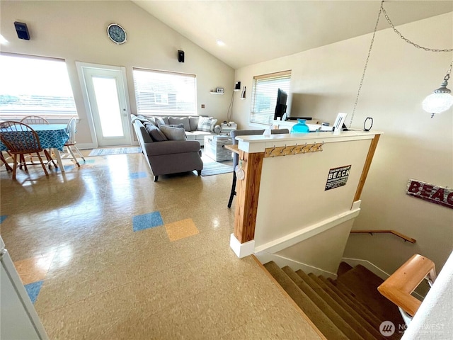living area featuring vaulted ceiling, light floors, and baseboards