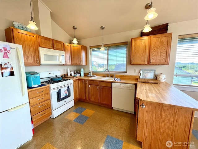 kitchen featuring white appliances, a sink, a peninsula, plenty of natural light, and lofted ceiling
