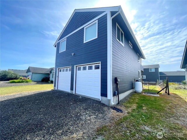view of side of property featuring an attached garage and asphalt driveway