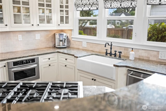 515 4th Ave SW, Puyallup, WA 98371 - kitchen featuring appliances with stainless steel finishes, a sink, glass insert cabinets, and white cabinetry