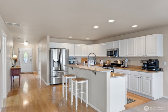 21032 Nordby Dr NW, Poulsbo, WA 98370 - kitchen with appliances with stainless steel finishes, light wood-style flooring, a breakfast bar, white cabinetry, and recessed lighting