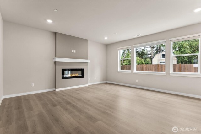 2406 Hyde Ct NE Unit 9, Olympia, WA 98506 - unfurnished living room with wood finished floors, a glass covered fireplace, baseboards, and recessed lighting