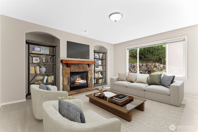 6336 286th Pl NE, Carnation, WA 98014 - carpeted living room featuring arched walkways, a stone fireplace, and baseboards