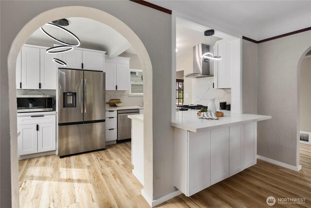 1602 NW 83rd St, Seattle, WA 98117 - kitchen featuring stainless steel appliances, wall chimney exhaust hood, arched walkways, and light wood finished floors