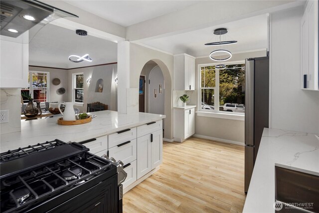1602 NW 83rd St, Seattle, WA 98117 - kitchen with black range with gas stovetop, freestanding refrigerator, arched walkways, white cabinets, and healthy amount of natural light