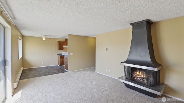 unfurnished living room with carpet floors, a ceiling fan, a baseboard radiator, a textured ceiling, and baseboards