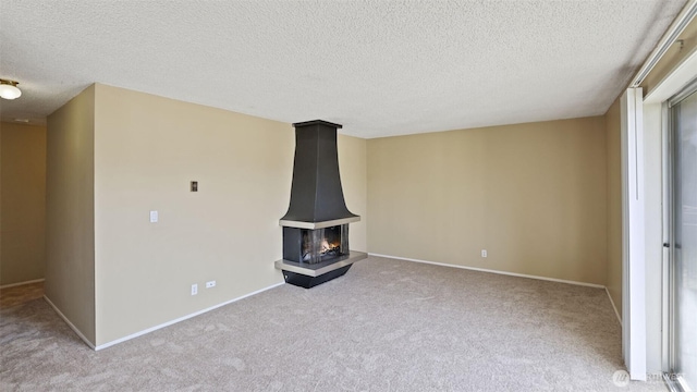 unfurnished living room with carpet flooring, a textured ceiling, and baseboards