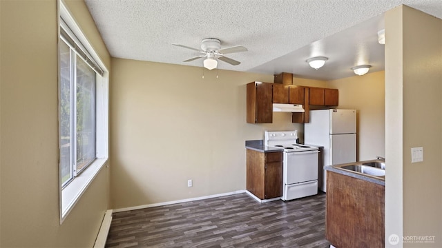 kitchen featuring white appliances, under cabinet range hood, dark wood-type flooring, a sink, and a ceiling fan