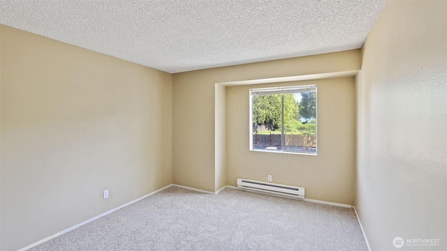 carpeted spare room featuring baseboard heating, baseboards, and a textured ceiling