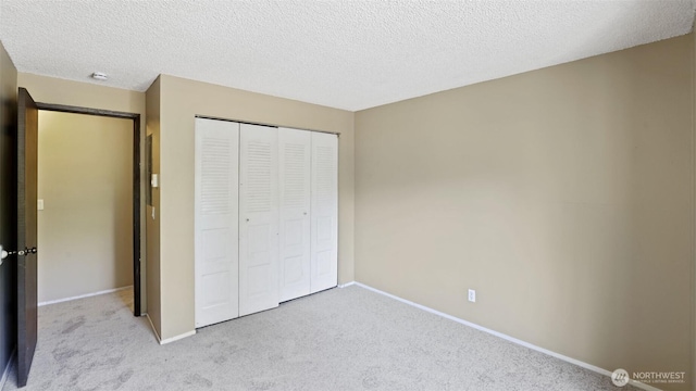 unfurnished bedroom with carpet floors, a closet, baseboards, and a textured ceiling