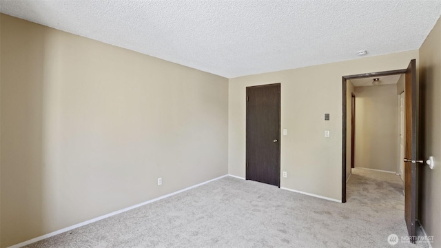 unfurnished bedroom with carpet flooring, a textured ceiling, and baseboards
