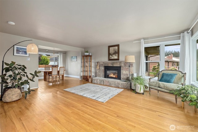 living room with wood finished floors, baseboards, and a stone fireplace
