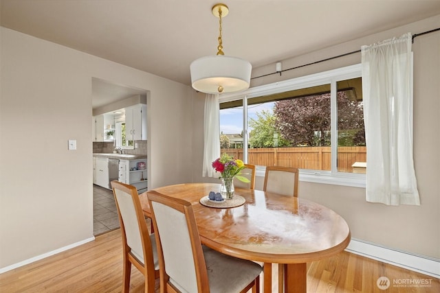 dining area featuring light wood finished floors, baseboards, and baseboard heating