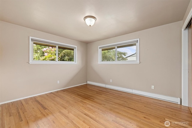 unfurnished room featuring plenty of natural light, light wood-style flooring, a baseboard radiator, and baseboards